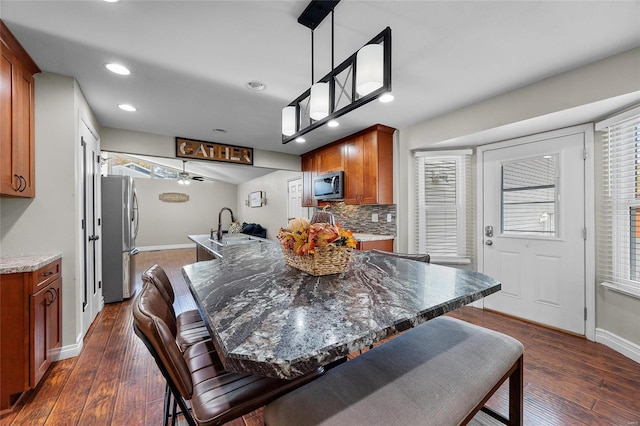 dining area featuring dark wood-type flooring, sink, and ceiling fan