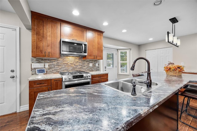 kitchen featuring a kitchen bar, an island with sink, appliances with stainless steel finishes, decorative backsplash, and sink