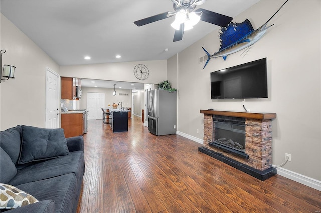 living room featuring dark wood-type flooring, lofted ceiling, a fireplace, and ceiling fan