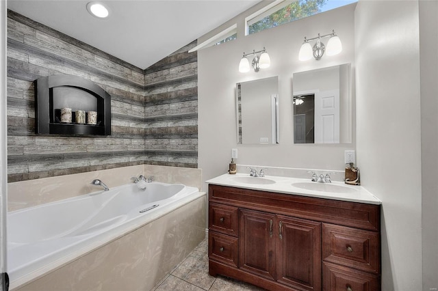 bathroom featuring vaulted ceiling, tile patterned flooring, a washtub, and vanity