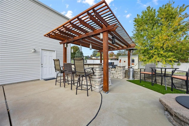 view of patio / terrace with exterior kitchen, a bar, and a pergola