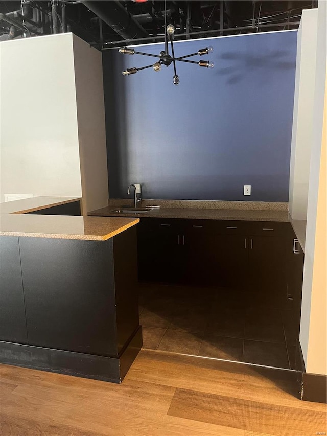 bar with light hardwood / wood-style flooring, sink, and a notable chandelier