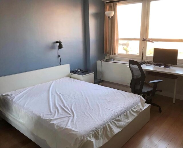 bedroom with built in desk and wood-type flooring