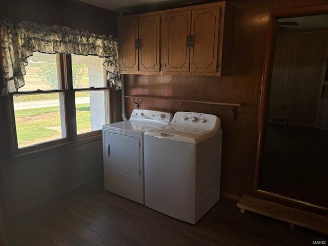 washroom featuring dark wood-type flooring, washer and dryer, cabinets, and wooden walls