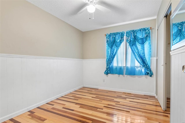 unfurnished room with light hardwood / wood-style floors, a textured ceiling, and plenty of natural light