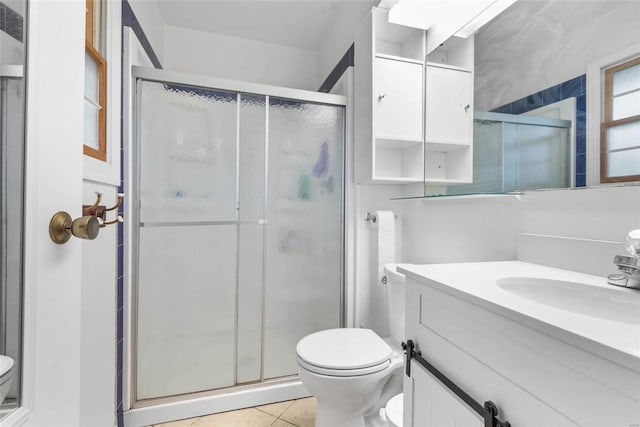 bathroom with vanity, a shower with shower door, toilet, and tile patterned floors