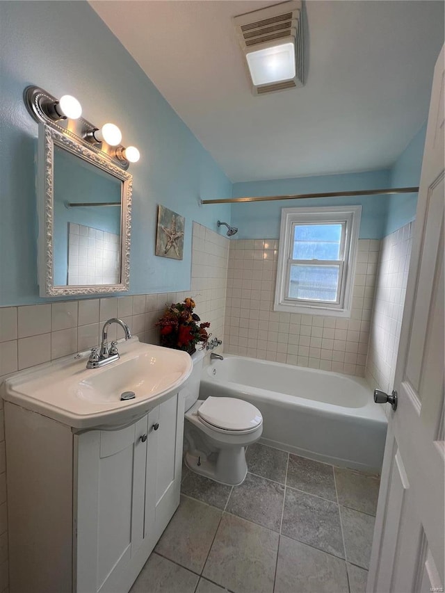 full bathroom featuring backsplash, tile walls, toilet, vanity, and tiled shower / bath combo