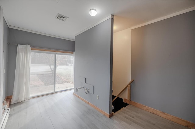 spare room with light wood-type flooring, a baseboard radiator, and ornamental molding