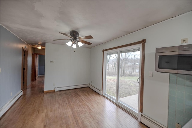 unfurnished room featuring baseboard heating, ceiling fan, and light wood-type flooring