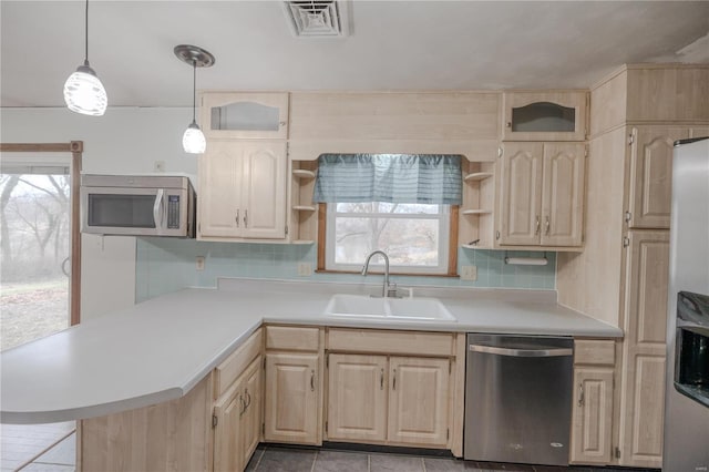 kitchen with sink, tasteful backsplash, kitchen peninsula, pendant lighting, and appliances with stainless steel finishes