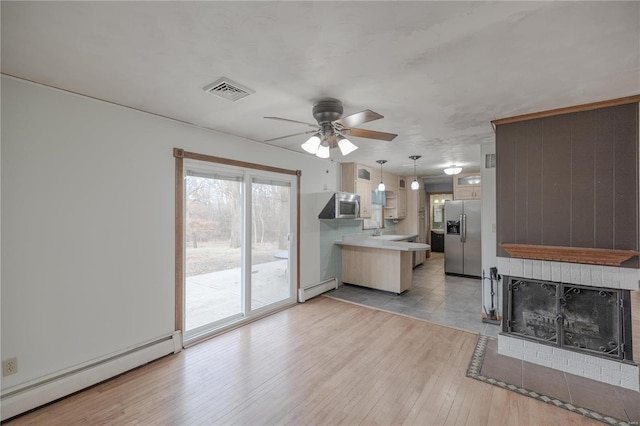 kitchen featuring ceiling fan, kitchen peninsula, stainless steel appliances, and a baseboard heating unit