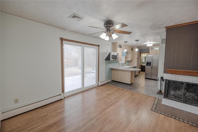 kitchen with pendant lighting, kitchen peninsula, baseboard heating, and stainless steel appliances