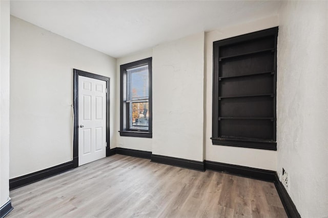 empty room featuring built in features and light wood-type flooring