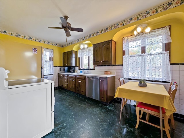 kitchen featuring sink, range, stainless steel dishwasher, tile walls, and ceiling fan