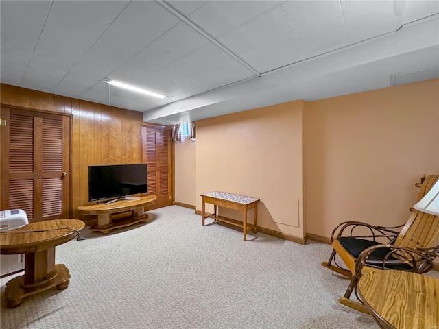 sitting room featuring wooden walls and carpet floors