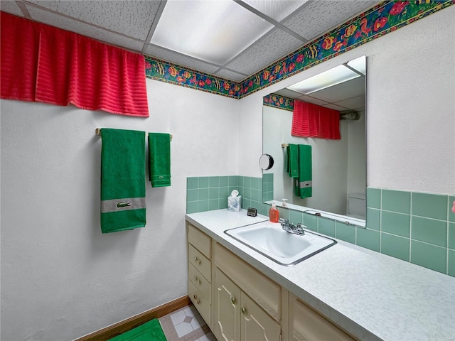 bathroom featuring vanity, tasteful backsplash, and a drop ceiling