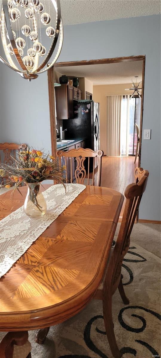 dining area featuring a notable chandelier, carpet, and a textured ceiling