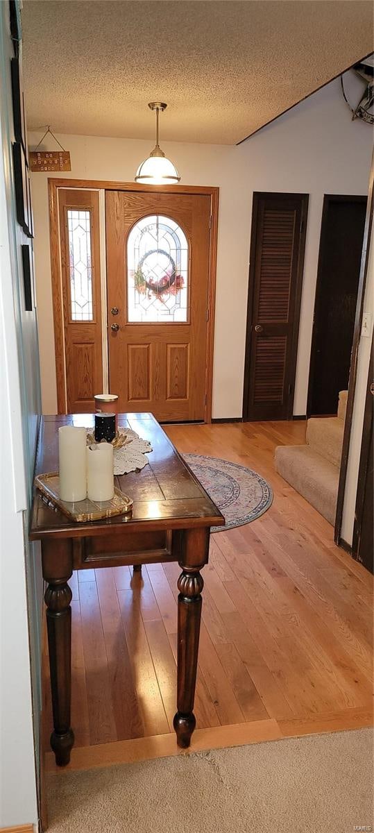 foyer with hardwood / wood-style flooring, a textured ceiling, and vaulted ceiling