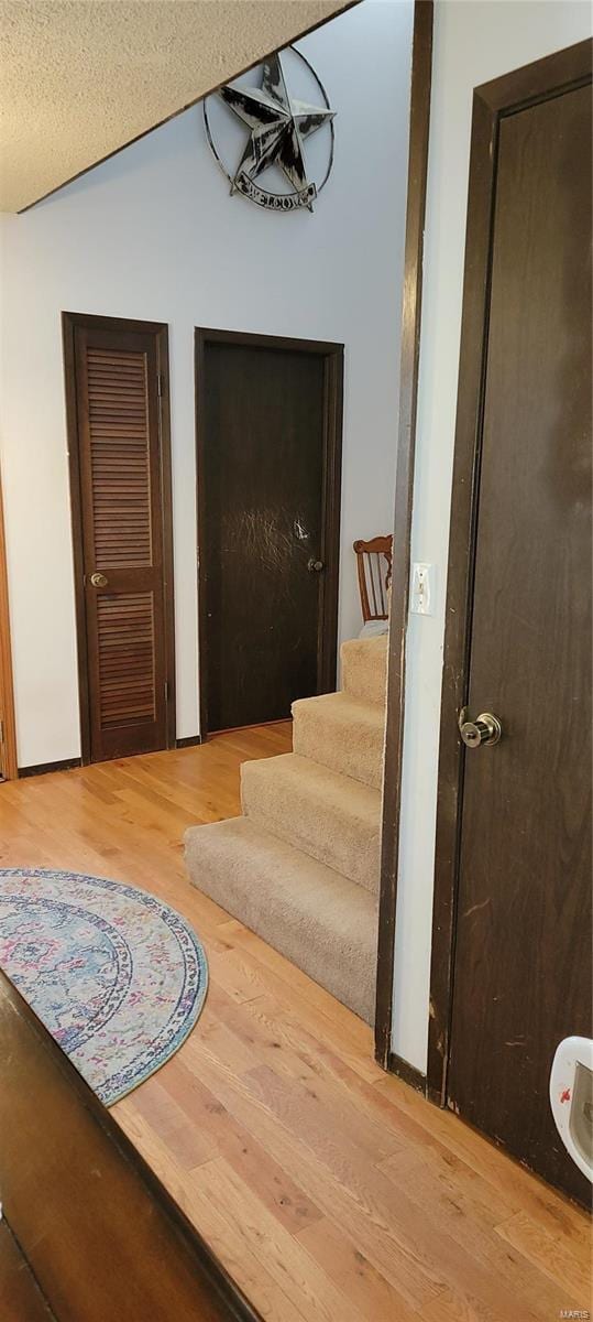 stairway with a textured ceiling and wood-type flooring