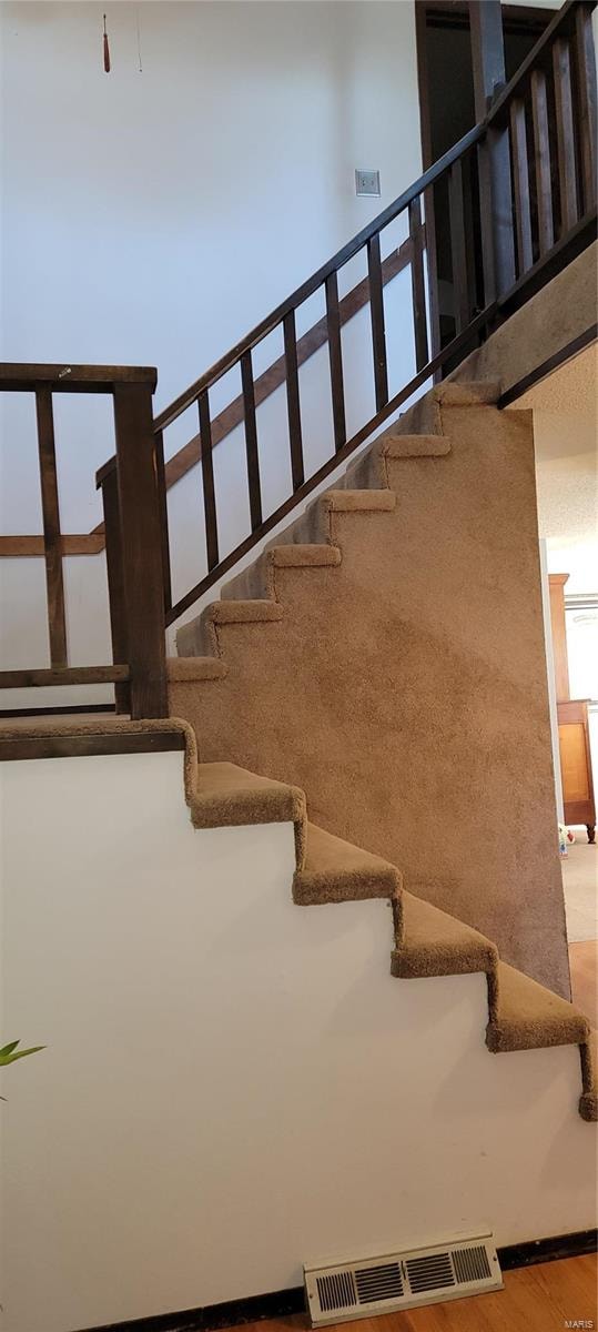 stairway featuring a towering ceiling and wood-type flooring