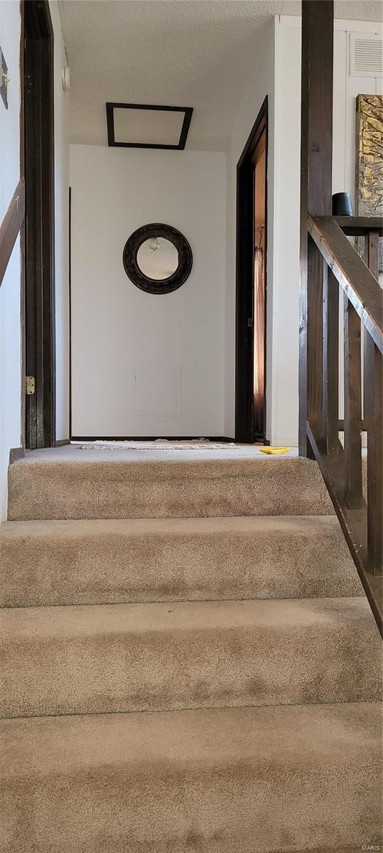 staircase featuring a textured ceiling