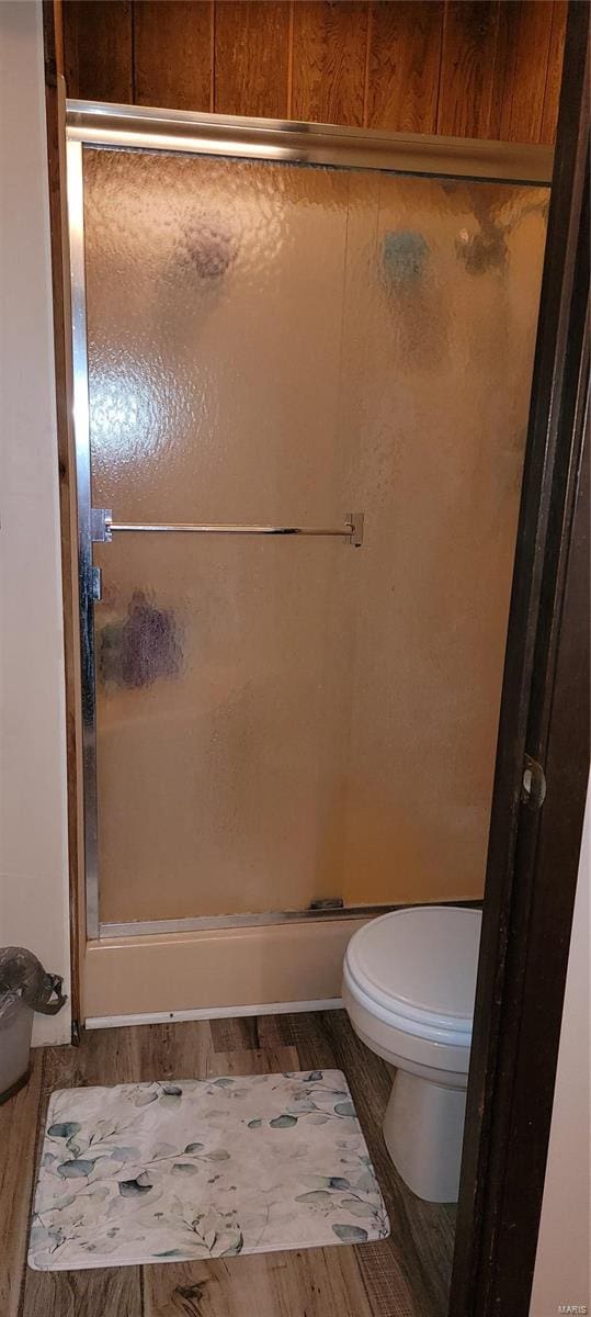 bathroom with toilet, hardwood / wood-style flooring, and a shower with door