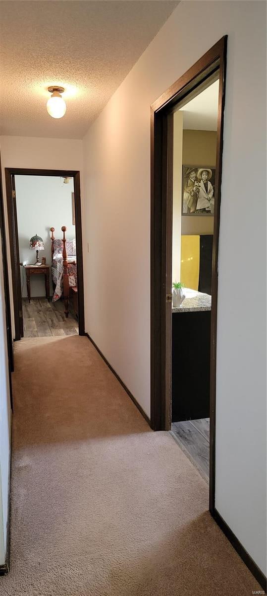 hallway featuring light carpet and a textured ceiling