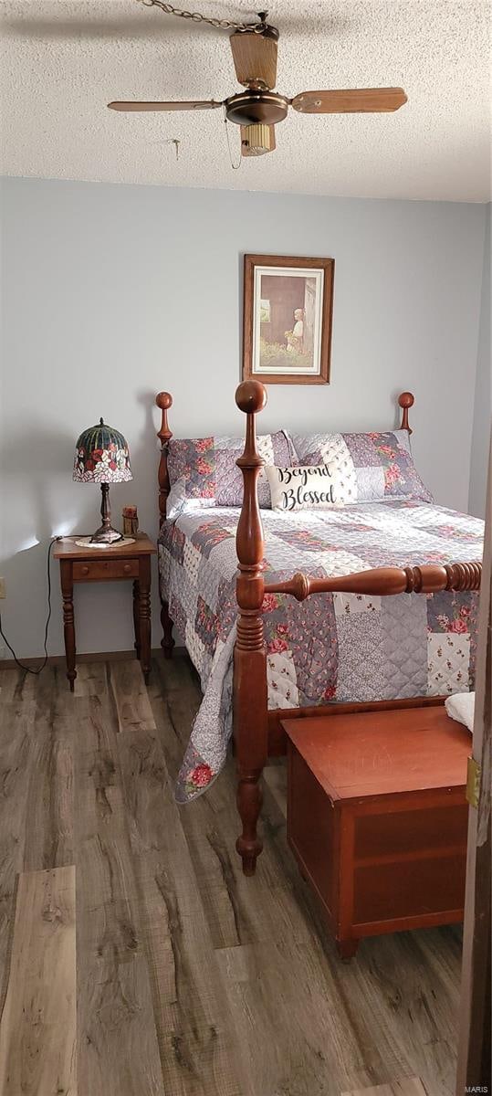 bedroom with dark hardwood / wood-style floors, a textured ceiling, and ceiling fan