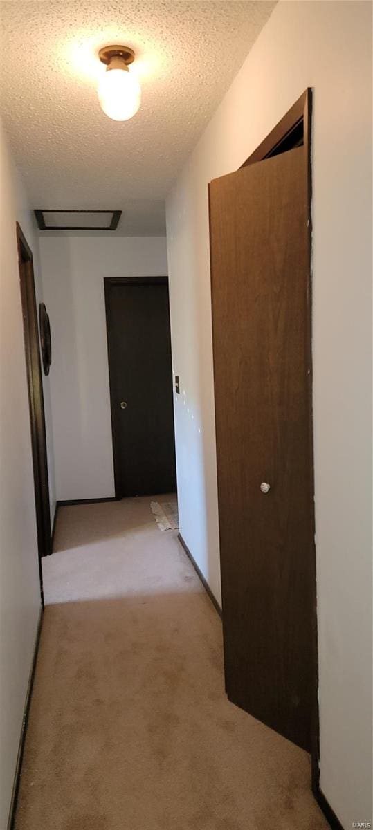 hall with light carpet and a textured ceiling