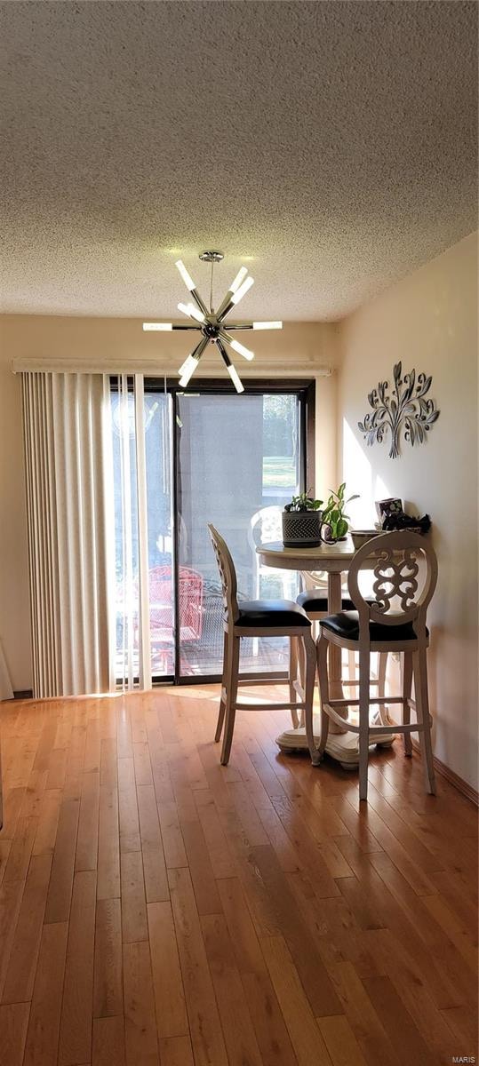 dining room with a notable chandelier, hardwood / wood-style flooring, and a textured ceiling