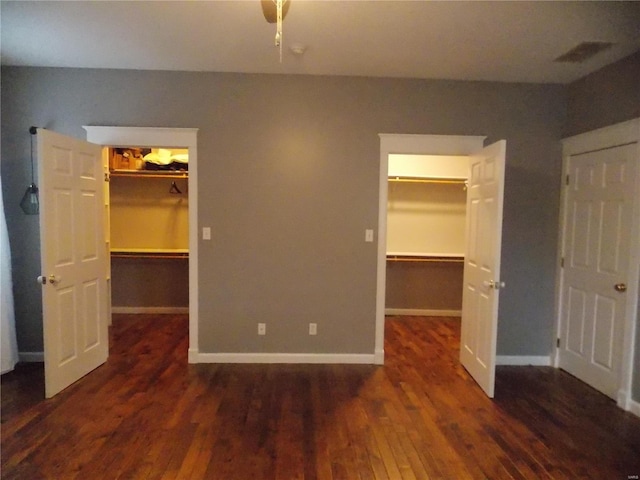 unfurnished bedroom featuring a spacious closet and dark hardwood / wood-style floors