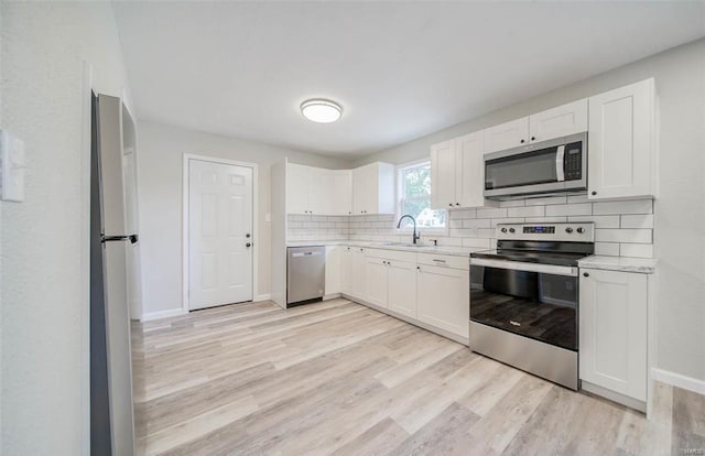 kitchen featuring white cabinetry, sink, light wood-type flooring, and appliances with stainless steel finishes