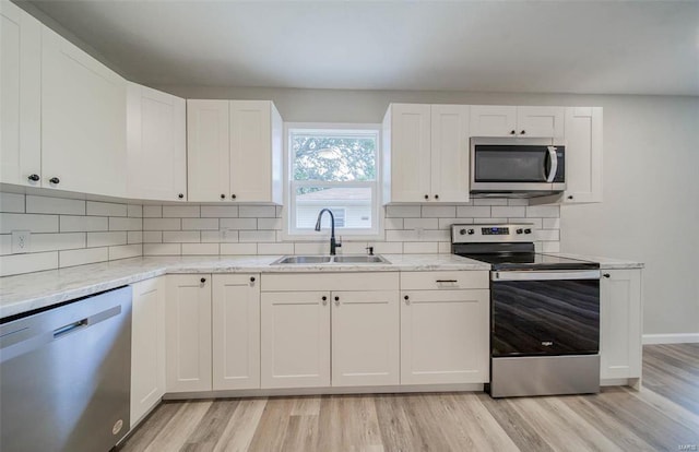 kitchen featuring light wood-type flooring, white cabinetry, light stone countertops, and stainless steel appliances