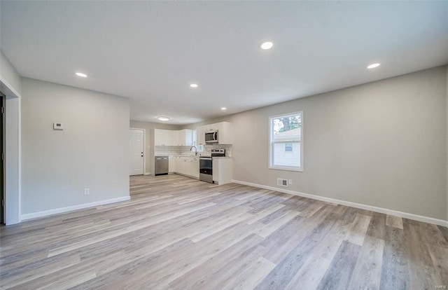 unfurnished living room with sink and light hardwood / wood-style flooring