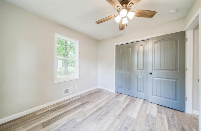 unfurnished bedroom with light hardwood / wood-style flooring, ceiling fan, and a closet