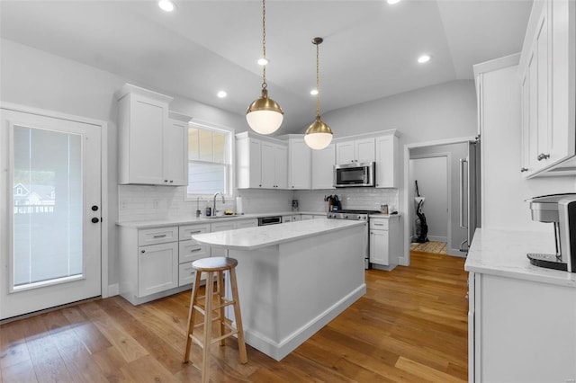 kitchen with appliances with stainless steel finishes, white cabinets, sink, and light hardwood / wood-style floors