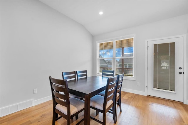 dining room featuring light wood-type flooring and vaulted ceiling