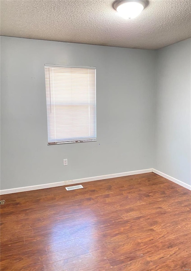 empty room with dark wood-type flooring and a textured ceiling