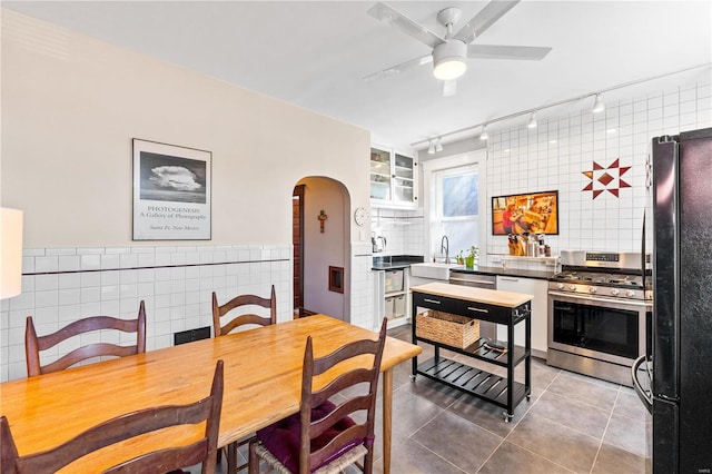 dining room with ceiling fan, tile patterned flooring, tile walls, and sink