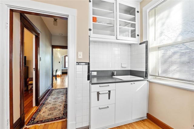 kitchen featuring decorative backsplash, white cabinets, and light wood-type flooring