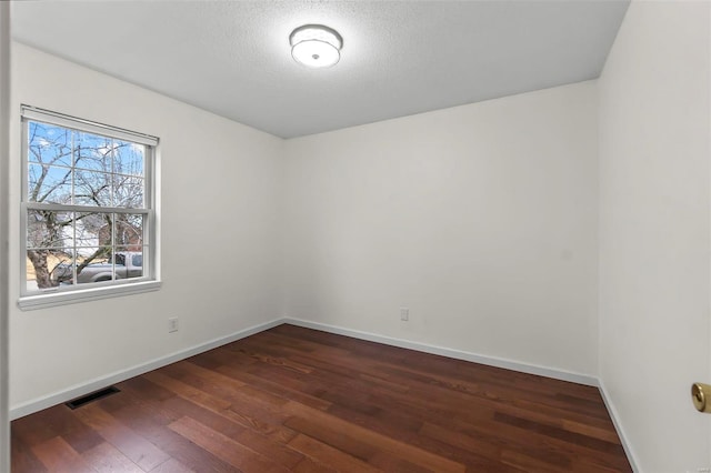 unfurnished room featuring dark wood-type flooring and a textured ceiling