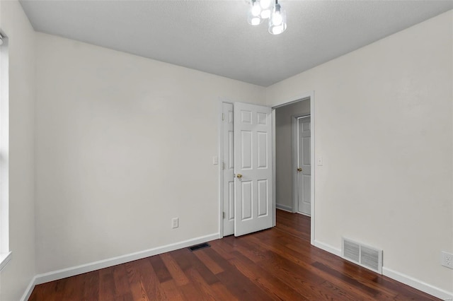 empty room with dark wood-type flooring and a textured ceiling