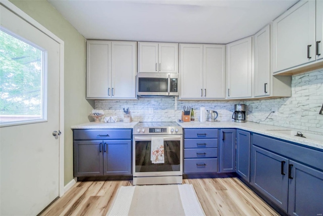 kitchen featuring blue cabinets, white cabinets, stainless steel appliances, and light hardwood / wood-style floors