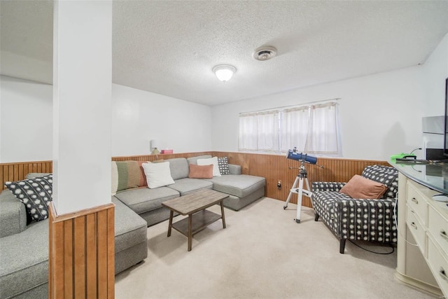 living room with wood walls, a textured ceiling, and light colored carpet