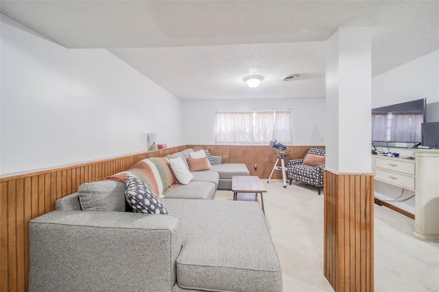 living room featuring light carpet, a textured ceiling, and wooden walls