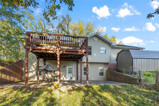 rear view of house with a wooden deck, a patio, and a storage unit