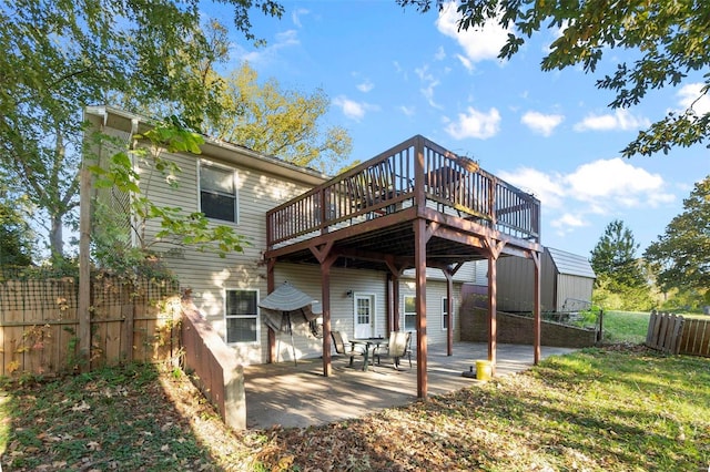 rear view of property with a wooden deck, a patio area, and a lawn