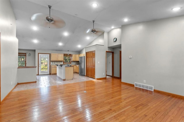 kitchen featuring a center island, stainless steel fridge, ceiling fan, light hardwood / wood-style floors, and high vaulted ceiling