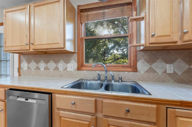 kitchen featuring tile countertops, stainless steel dishwasher, sink, and backsplash