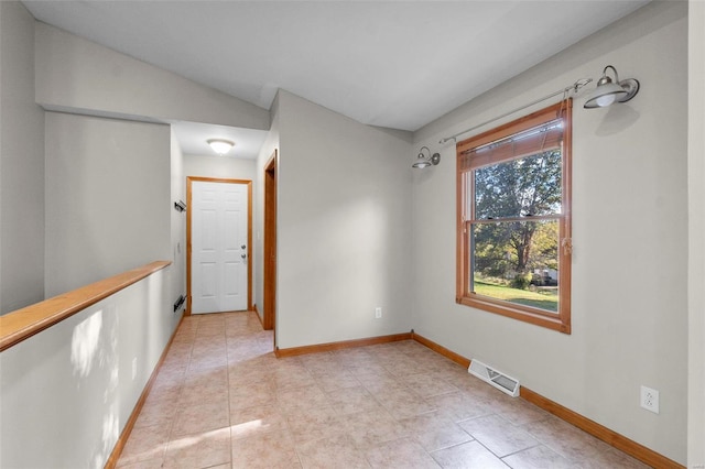 tiled spare room featuring vaulted ceiling